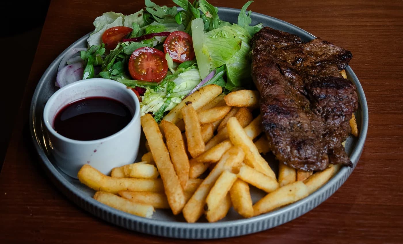 Flame-grilled steak served with chips, salad and sauce at The Old Forge